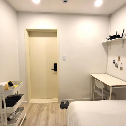 a room with a door and a bed and a desk at Humming stay in Seoul