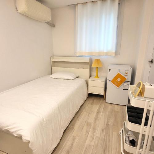 a small bedroom with a white bed and a window at Humming stay in Seoul