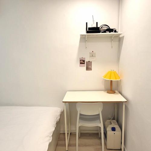 a table with a lamp and a chair next to a bed at Humming stay in Seoul