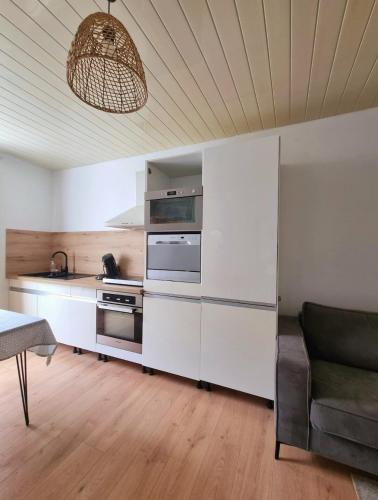 une cuisine avec des armoires blanches et un canapé dans une pièce dans l'établissement Appartement L'Hirondelle, à Anduze