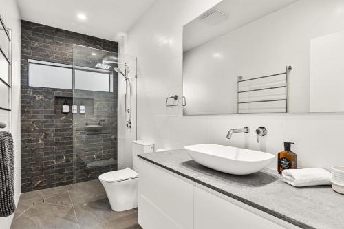 Un baño blanco con lavabo e inodoro. en The Corlette Beach Retreat, en Corlette