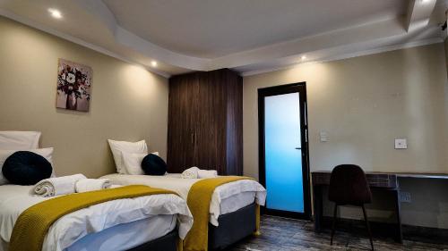 a hotel room with two beds and a desk at Ondjo Yetu in Benoni