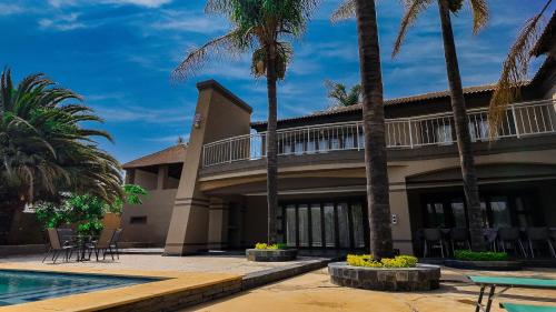 a building with palm trees and a swimming pool at Ondjo Yetu in Benoni