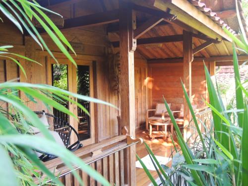 a porch of a wooden cabin with a table and chairs at Imalee - Cottage in Yogyakarta
