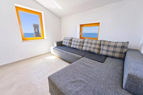 a living room with a couch and two windows at Apartments Punta Piran in Piran
