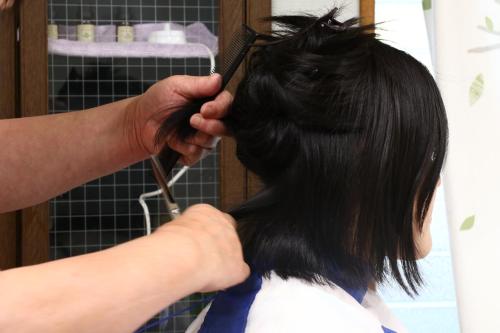 a person cutting a persons hair with a scissors at 森の風 in Higashiizu