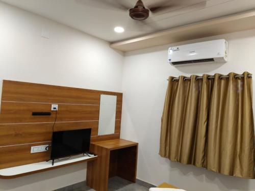 a room with a tv and a curtain at Ayodhya Bhavan - Home Stay, Dwarka in Dwarka