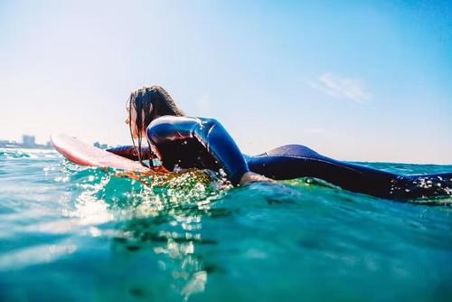 a woman laying on a surfboard in the water at Surf Stay ITOSHIMA in Itoshima