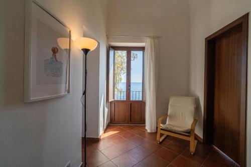 a hallway with a floor lamp and a chair and a door at Casa Scala in Acireale