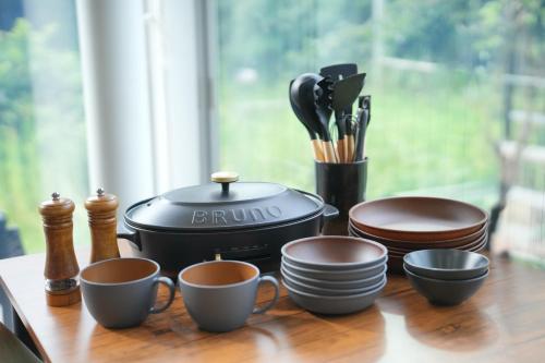 a table with cups and plates and a slow cooker at グランピング宿 星空テラス&暖炉の庭付き戸建 Orion in Miyamae