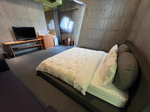 a bedroom with a large bed and a television at Smoking Rock in Jiaoxi