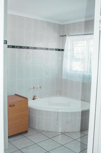 a white bathroom with a tub and a window at 7 Eland Boutique Guest House in Ladismith