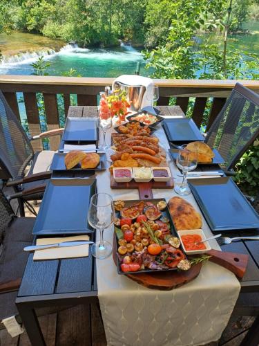 a table with plates of food and wine glasses at Eko Kamp odmorište Brig in Duga Resa
