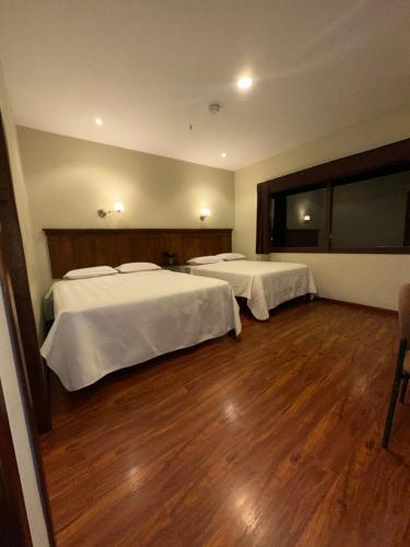 two beds in a room with wooden floors at Hotel & Suites El Quijote in Cuenca