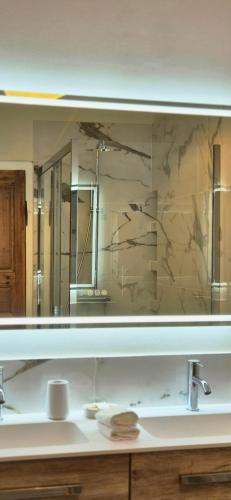 La salle de bains est pourvue d'un grand miroir et d'un lavabo. dans l'établissement Le Moulin Charme & Nature, à Esplantas