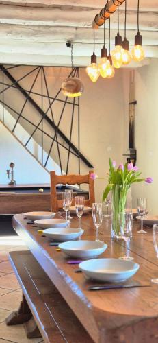 - une longue table en bois avec des assiettes et des verres à vin dans l'établissement Le Moulin Charme & Nature, à Esplantas
