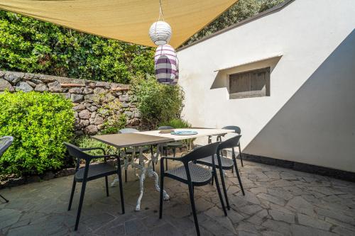 a table and chairs on a patio with a stone wall at Casa Scala in Acireale