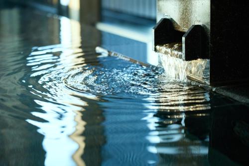 a pool with water pouring out of a fountain at Atami Izusan Karaku in Atami
