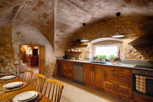 a kitchen with wooden cabinets and a table with chairs at Mas Piarnau in Vilasacra