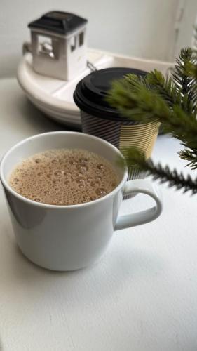 a cup of coffee on a table with a christmas tree at Lentävä Kalakukko -Veturi B&B in Kuopio