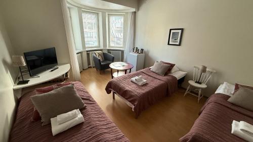 a small room with two beds and a television at Lentävä Kalakukko -Veturi B&B in Kuopio
