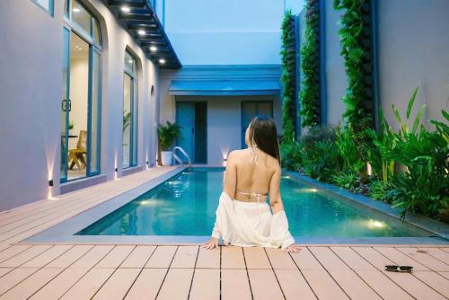 a woman in a white dress sitting next to a swimming pool at Villa Amanda 3 - City Center- Private swimming Pool in Phan Thiet