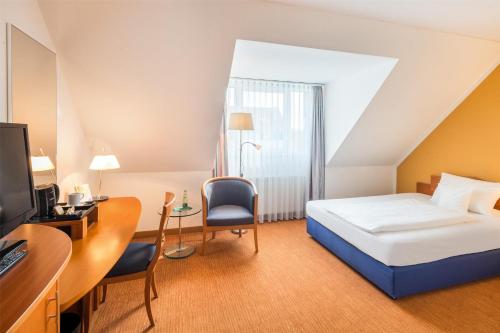 a bedroom with a bed and a desk with a computer at Best Western Hotel Am Straßberger Tor in Plauen