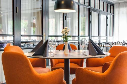 a dining room with a table and orange chairs at Scandic Gävle Väst in Gävle