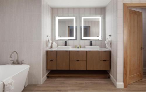 a bathroom with two sinks and a tub and two mirrors at Hilton Dallas/Plano Granite Park in Plano