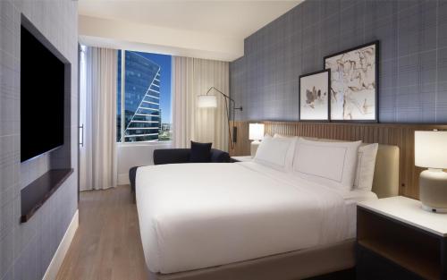 a hotel room with a white bed and a tv at Hilton Dallas/Plano Granite Park in Plano
