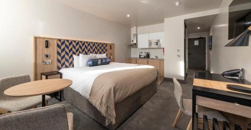 a hotel room with a bed and a table and chairs at Sandman Signature Glasgow Hotel in Glasgow
