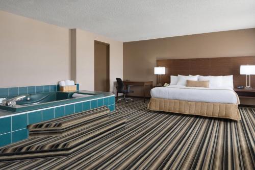 a hotel room with a bed and a bath tub at Days Inn by Wyndham Dalhousie in Dalhousie