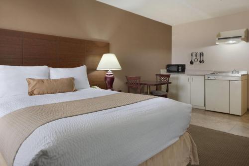 a hotel room with a large bed and a kitchen at Days Inn by Wyndham Dalhousie in Dalhousie