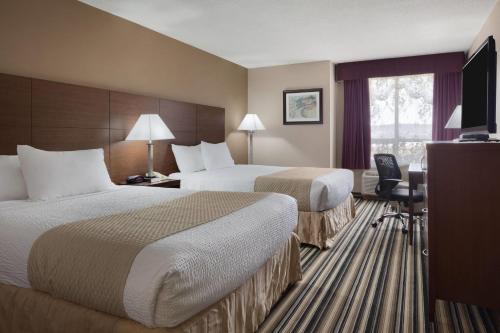 a hotel room with two beds and a television at Days Inn by Wyndham Dalhousie in Dalhousie