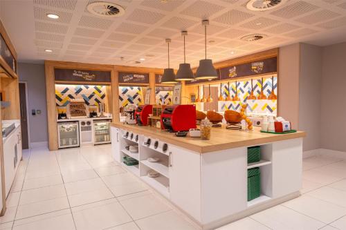 a large kitchen with a counter with red chairs at Hampton By Hilton Bristol Airport in Redhill