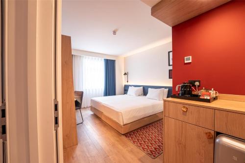 a bedroom with a bed and a red wall at Hampton By Hilton Bristol Airport in Redhill