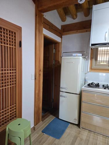 a kitchen with a white refrigerator and a green stool at Hanok Myeongdang in Gyeongju