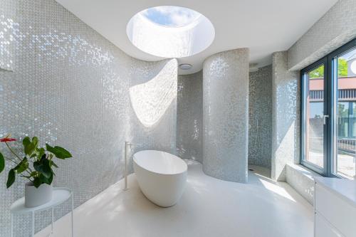 ein Badezimmer mit einer weißen Badewanne und einer Topfpflanze in der Unterkunft Flexible SelfCheckIns 140 - The most Luxurious Villa with Private pool in Zagreb in Zagreb