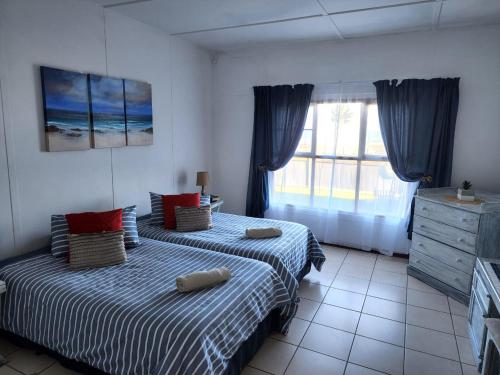 ein Schlafzimmer mit zwei Betten und einem Fenster in der Unterkunft DE SWARTE MOSSEL in Hondeklipbaai