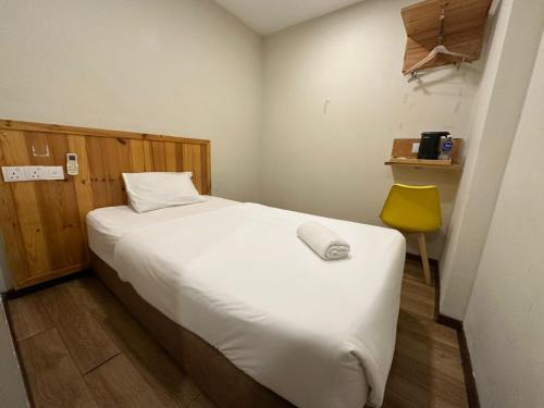 a bedroom with a white bed and a yellow chair at Swing & Pillows - Apple Hotel Shah Alam in Shah Alam