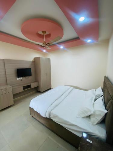 a bedroom with a bed and a ceiling with a tv at Modest Rooms By Libra in Khizrābād