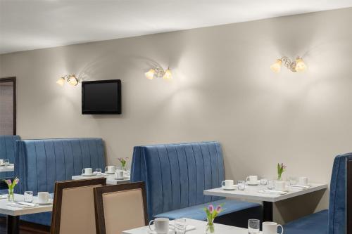 a dining room with tables and blue chairs and a tv at National Hotel Jackson, Tapestry Collection by Hilton in Jackson