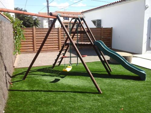 a swing set in a yard with green grass at Maison bord de mer 3 chambres in Les Sables-dʼOlonne