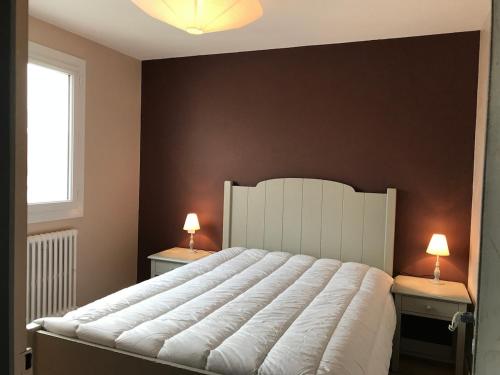 a bedroom with a large white bed with two lamps at Maison bord de mer 3 chambres in Les Sables-dʼOlonne