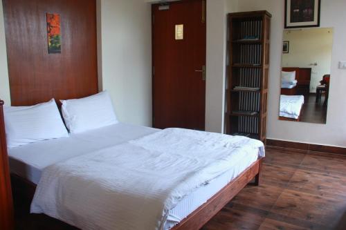 a bedroom with a large bed with white sheets at The Sojourn in Dharamshala