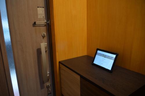 a laptop sitting on top of a dresser next to a door at BEPPU つばき 一棟貸切宿 鉄輪温泉まで車で4分 石風呂付 無料駐車場3台 最大6名 wifi無料 in Beppu
