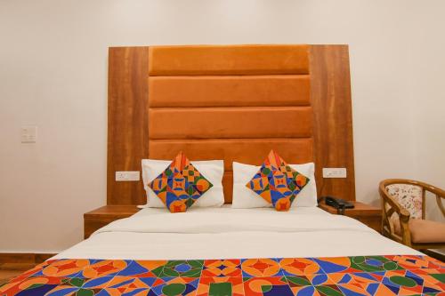 a bedroom with a bed with a wooden headboard at FabHotel Ambassador in Chandīgarh