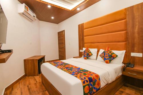 a bedroom with a large bed with a wooden headboard at FabHotel Ambassador in Chandīgarh
