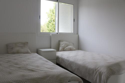 2 camas en una habitación blanca con ventana en 3C Fuerteventura, en Costa Calma