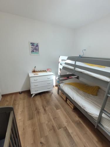 a bedroom with two bunk beds and a dresser at Maison à la campagne proche de La Rochelle in Sainte-Soulle